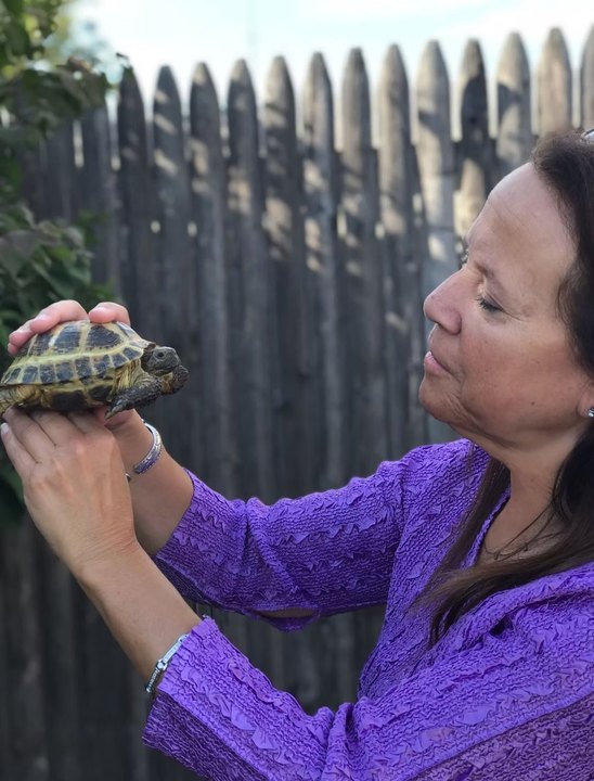 Donna Sue Rosenthal holding a tortoise up at eye level outdoors
